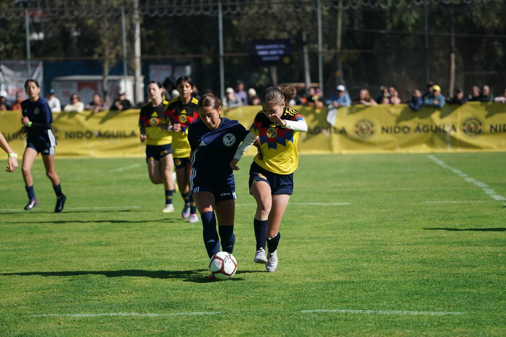 A young player driving forward with the ball during a match